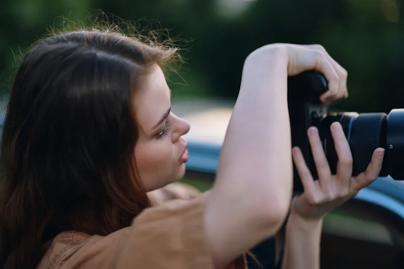Young photographer focused on capturing images outdoors, showcasing creativity, passion for photography, and a serene nature background.
