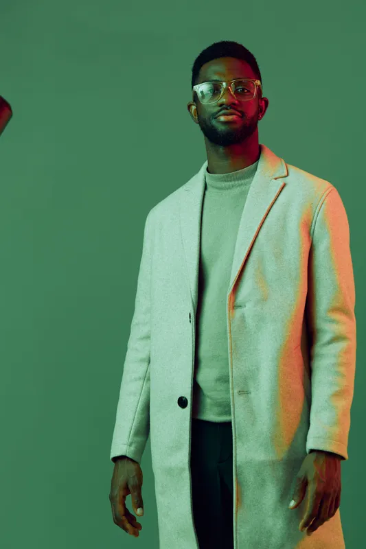 Stylish male model in a modern winter coat against a green background, showcasing contemporary fashion and confidence for winter collections and lifestyle branding