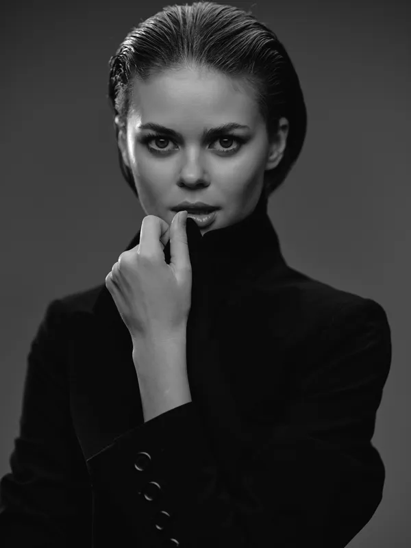 Black and white portrait of a serious woman in a turtleneck sweater with thoughtful expression and elegant pose