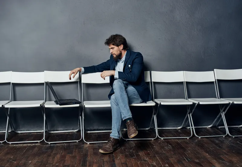 Деловой мужчина в костюме сидит на стуле перед ноутбуком, работая в стиле lifestyle