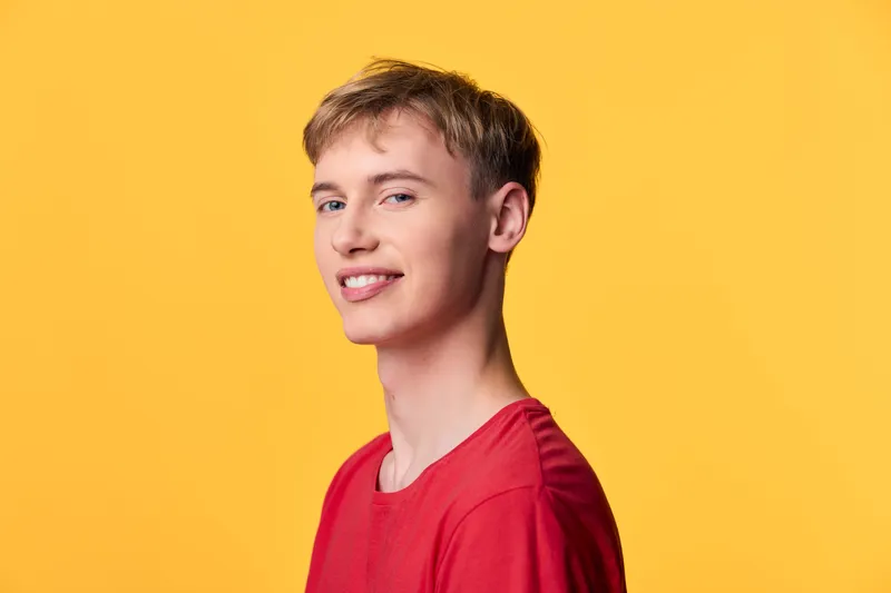 Smile, young man in redshirt against yellowbackground, a clean headshot conveying positivity, energy and casual fashion vibe for lifestyle and branding use