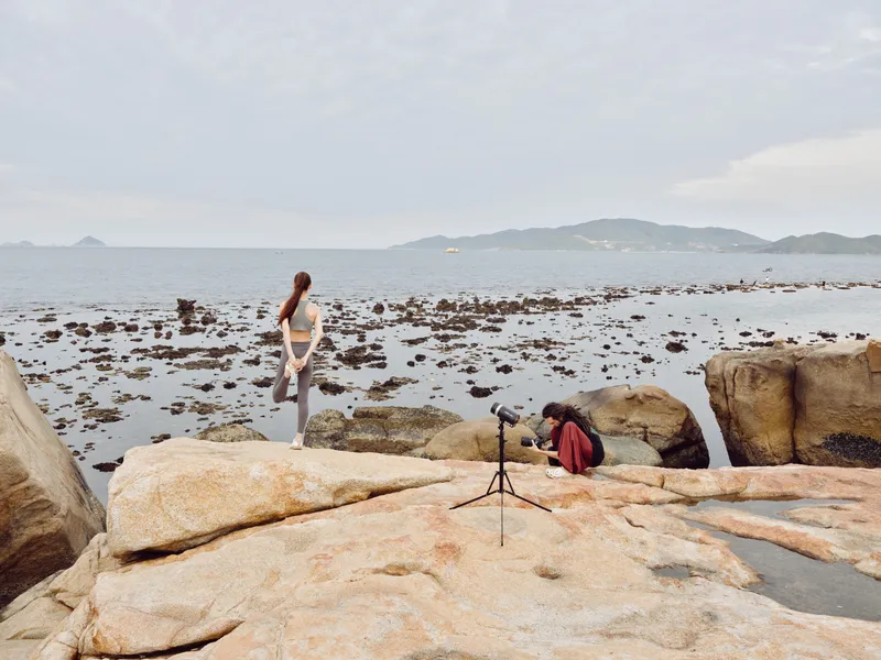 Serene yoga practice by the ocean with a focused female model in athletic wear, emphasizing relaxation and wellness amidst nature