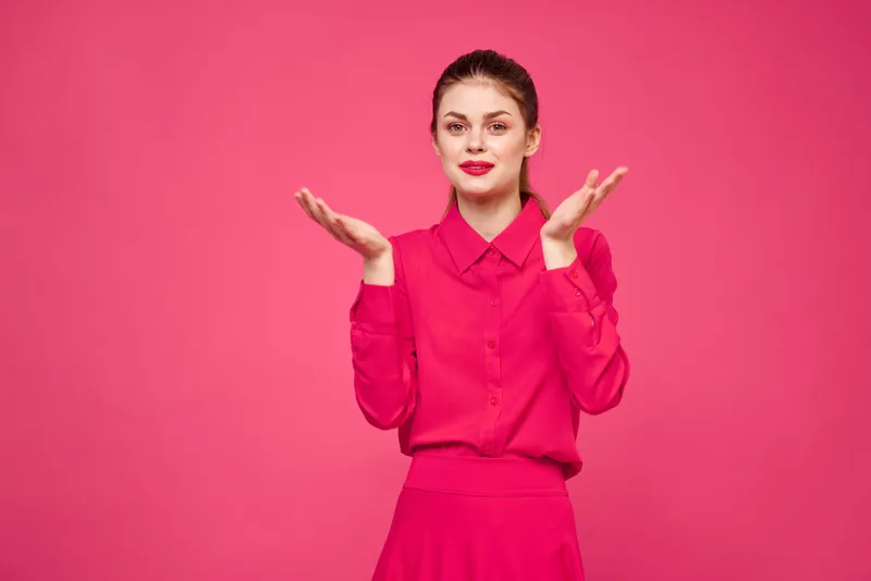 Женщина на розовом фоне в модной одежде, с ярким макияжем и причёской, модель