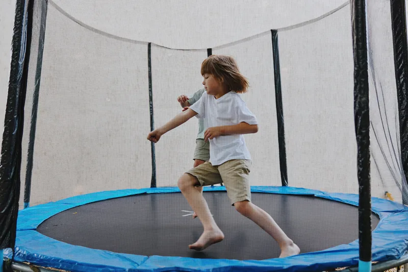 Active children playing on a trampoline, showcasing joy and excitement during outdoor fun, surrounded by a vibrant atmosphere of laughter and playfulness.