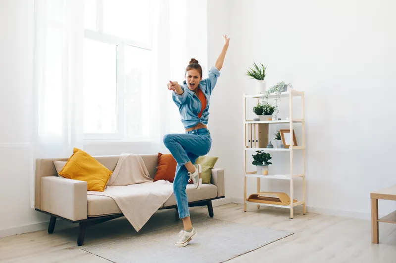 Радостная женщина прыгает под музыку в игривой концепции домашнего интерьера
