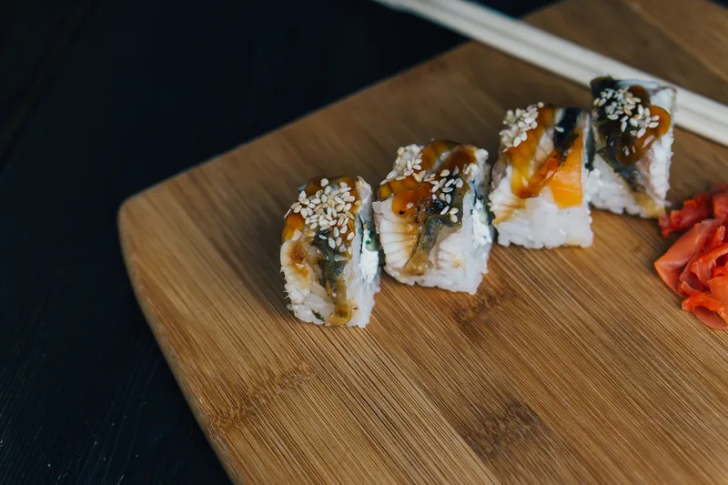 Роллы суши с палочками для еды, японская кухня на деревянной доске