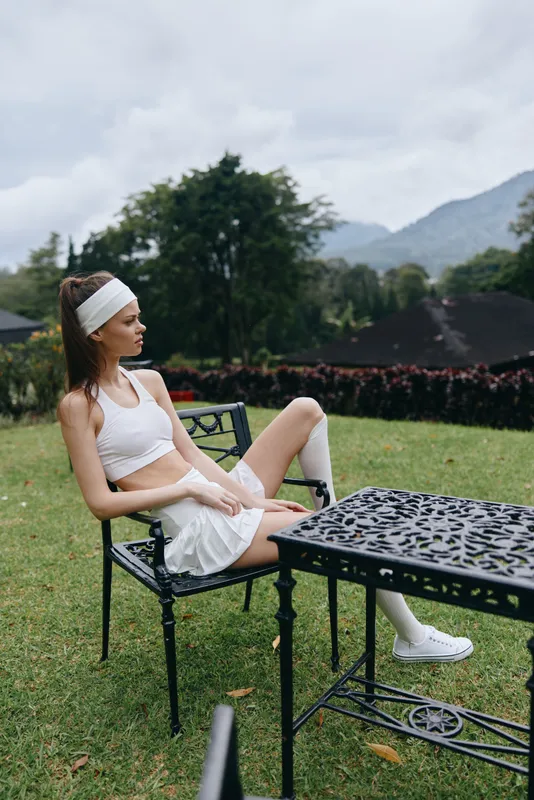 Young athletic woman in sportswear sitting outdoors, showcasing a healthy lifestyle and relaxation with nature in the background, perfect for fitness and wellness themes