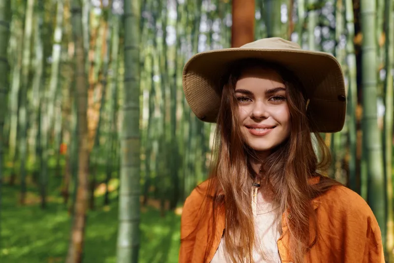 woman smile hat bamboo forest portrait nature outdoors young happy - closeup portrait of a young woman in a wide hat and orange jacket, smiling in sunlit bamboo grove, natural relaxed lifestyle scene
