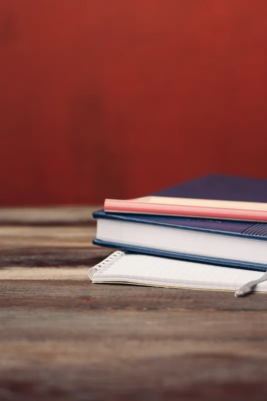 Книги, блокноты, ручки на деревянном столе, карандаш, офис, письменные принадлежности