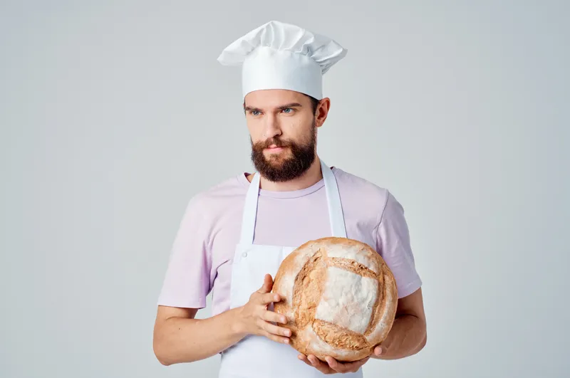 Бородатый мужчина в фартуке занимается приготовлением еды на кухне ресторана