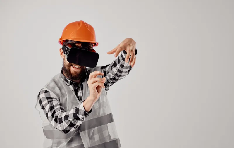 Строительный рабочий в оранжевой каске и 3D-очках жестикулирует руками, свободное пространство