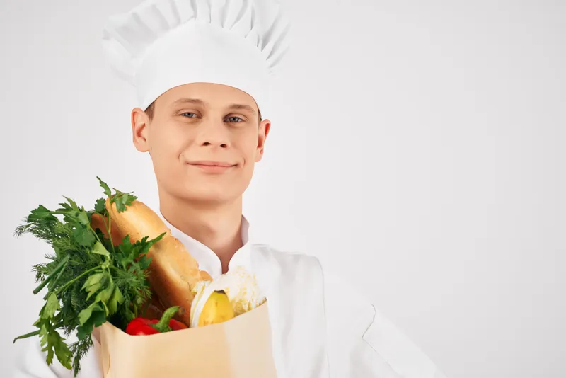 Весёлый мужчина-шеф-повар с упаковкой продуктов на кухне
