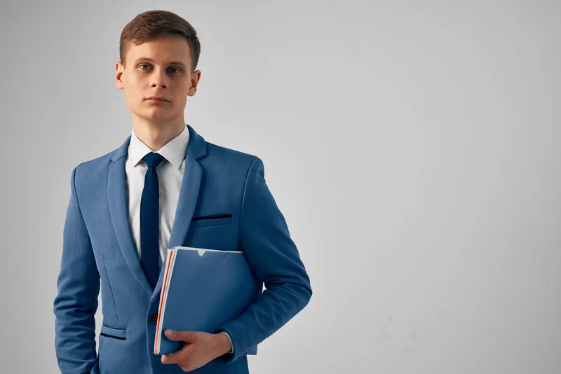 Мужчина в деловом костюме держит в руках синюю папку