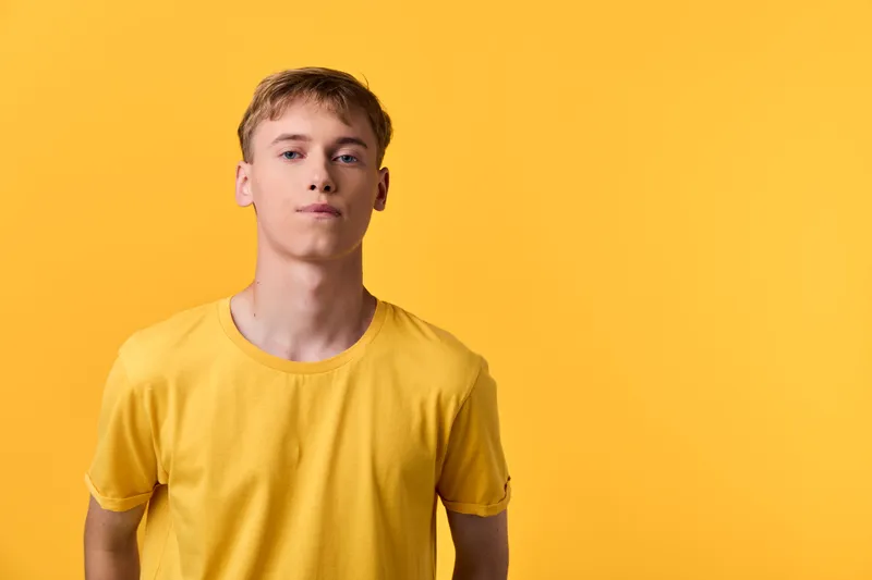 yellow shirt, young man, bright backdrop, casual, minimalism, lifestyle, Yellow shirted young man stands against a bright yellow backdrop, casual minimalism, relaxed pose, clean lighting, lifestyle
