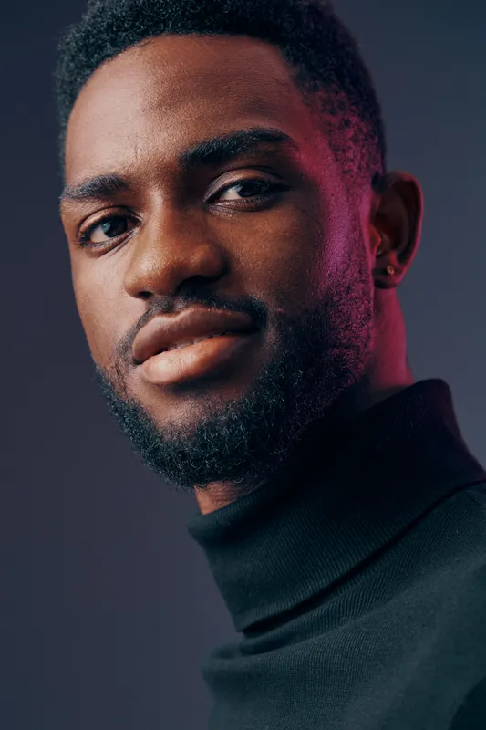Portrait of a confident Black man in a stylish turtleneck sweater, expressing self assurance with a subtle smile against a soft gradient background