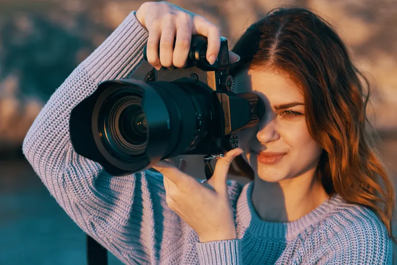 Красивая женщина-фотограф на природе в горах фотографирует модель на фоне пейзажа