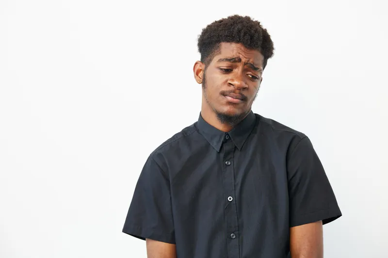 Black man with thoughtful expression, dressed in casual black shirt. Reflecting emotion, capturing the essence of inner contemplation and self-discovery.
