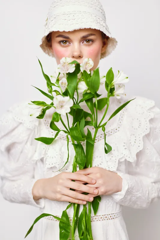Young woman in a white dress holding fresh flowers, exudes a soft and gentle emotion, perfect for seasonal and nature themed concepts