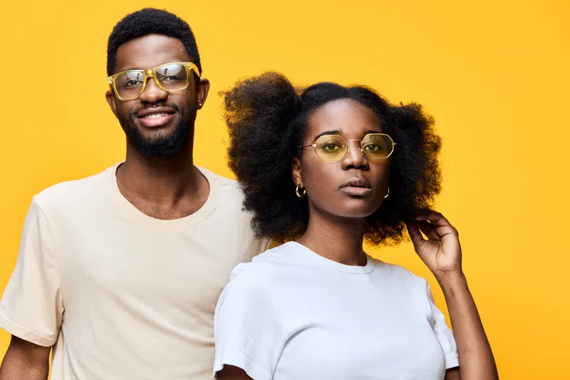 Two African models with stylish glasses against a bright yellow background, showcasing modern fashion and vibrant emotions in a summer themed concept