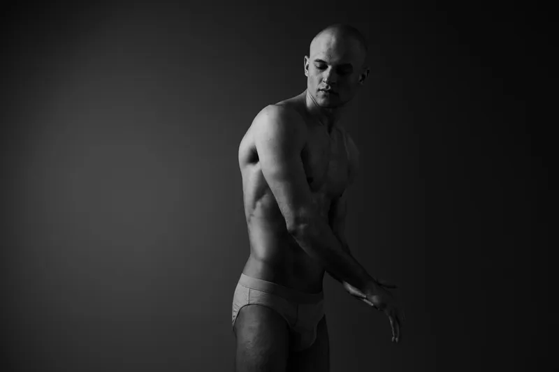 Black and white image of a thoughtful man, showcasing elegance and strength through body language and posture, evoking a sense of introspection.