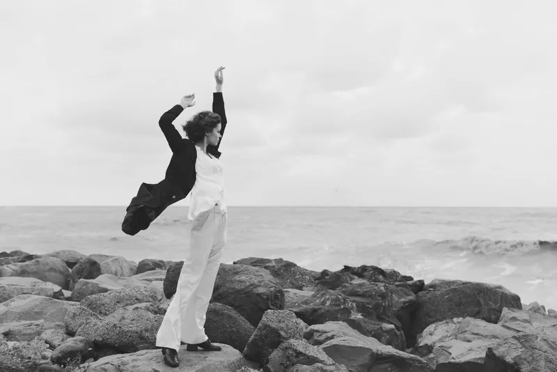 Dance, dancers, sea, rocks, joy, movement on rugged shoreline as two figures leap in harmony, monochrome capture of motion and freedom along the coast