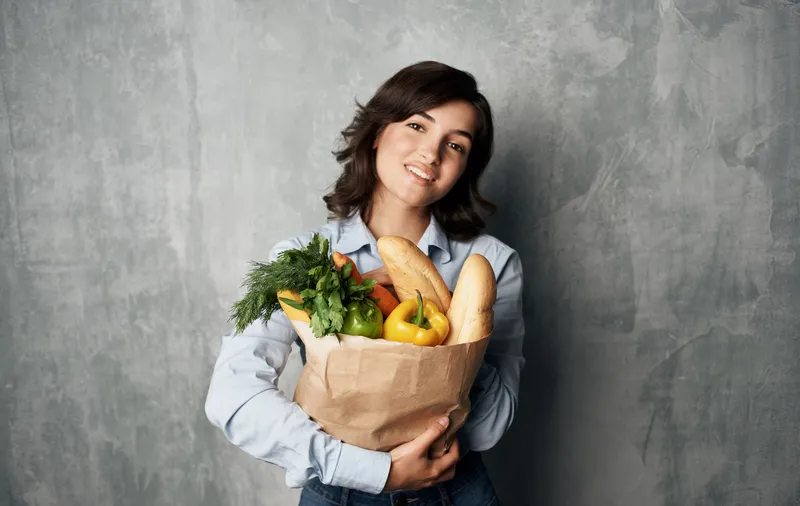 Жизнерадостная брюнетка с пакетом продуктов, доставка покупок