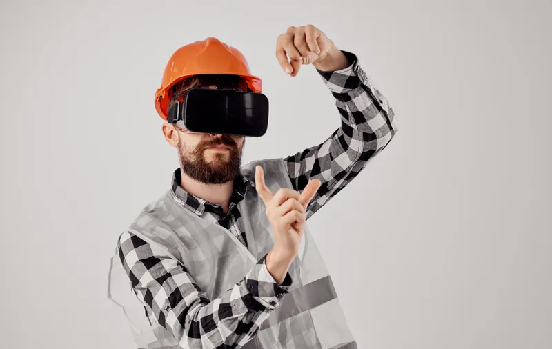 Строитель в оранжевой каске и 3D-очках жестикулирует руками