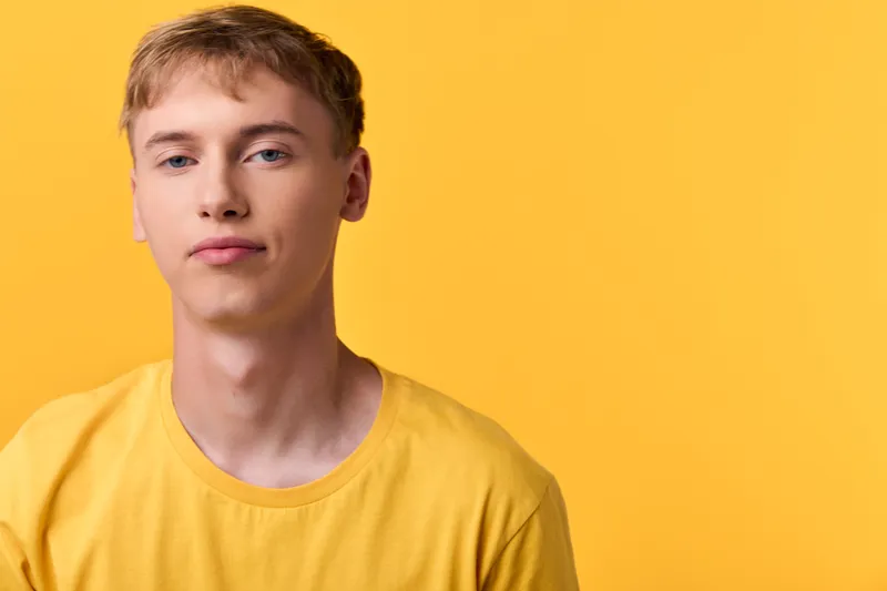 Close up of a young man, male, in a yellow shirt against a yellow background, casual and confident, highlighting clean lines and modern style with a simple non branded look