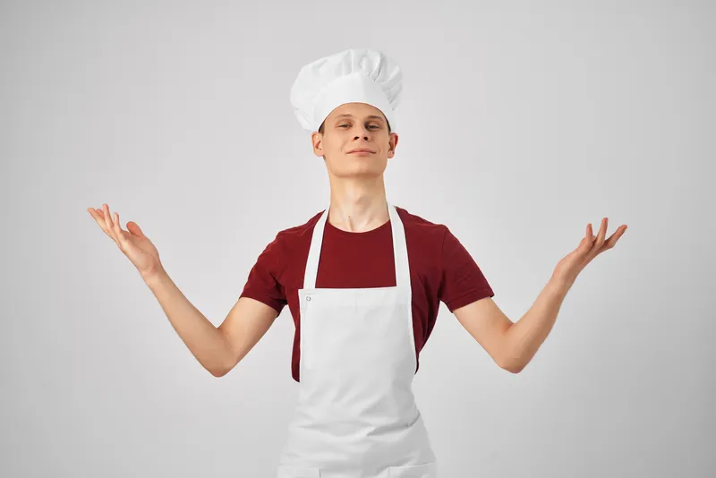 Мужчина-повар в униформе работает на кухне ресторана, занимаясь приготовлением пищи