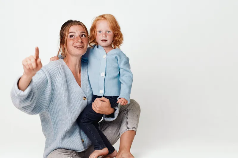 Мать и ребенок обсуждают камеру в гостиной во время семейной фотосессии для блога о путешествиях и образе жизни