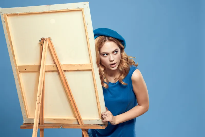 Женщина-художница с мольбертом и синей краской занимается своим хобби — рисованием