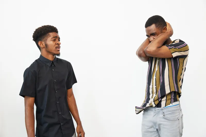 Two black men expressing various emotions against a minimalist background. One appears curious while the other is feeling overwhelmed. A powerful representation of human connection.