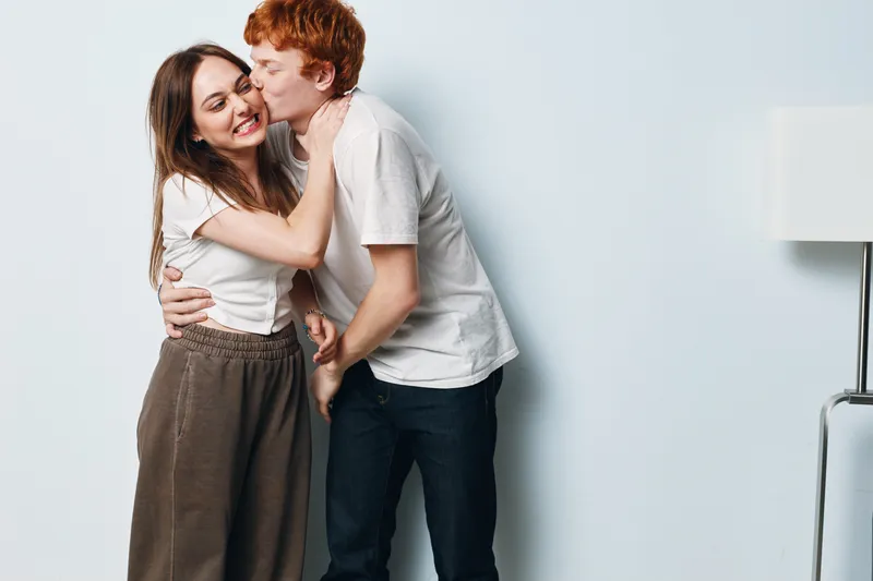 Couple, embrace and kiss with love and happiness in casual clothes at home interior. Young man and woman with affection for relationship, romance and connection in living room.
