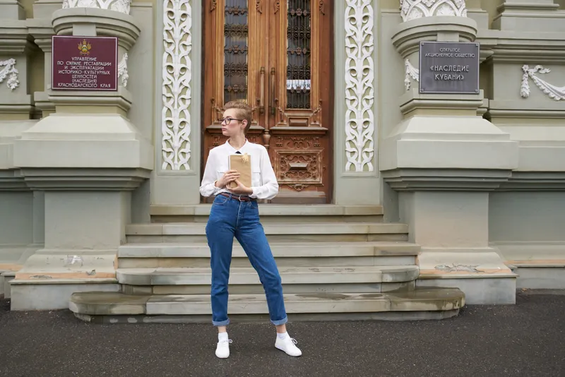 Симпатичная женщина с книгой в руках на открытом воздухе, читает и занимается самообразованием