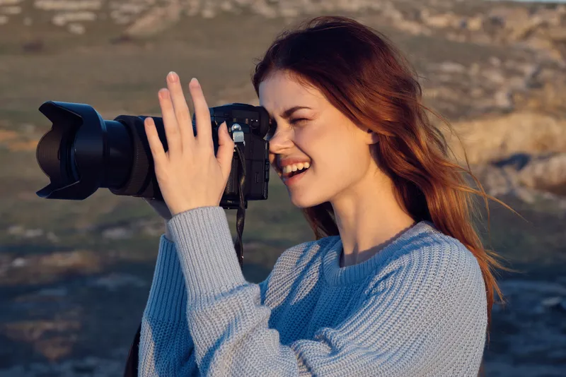 Женщина-профессиональный фотограф на открытом воздухе, занимается хобби и работой, на фоне пейзажа