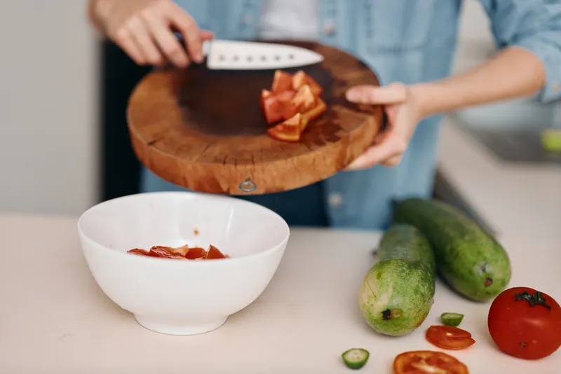 Свежая кухня: здоровое и яркое кулинарное исследование женщины среди органических овощей, она режет с точностью