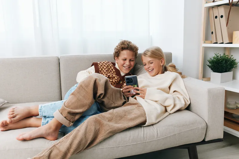 Authentic moment of friends at home enjoying playful downtime, capturing school life, relaxed lifestyle, comfort, and genuine connection as they share laughter and a candid mood.