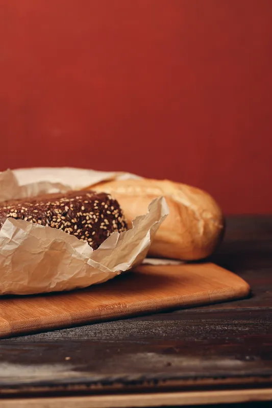 Буханка хлеба на разделочной доске, выпечка, мучной продукт, красный фон