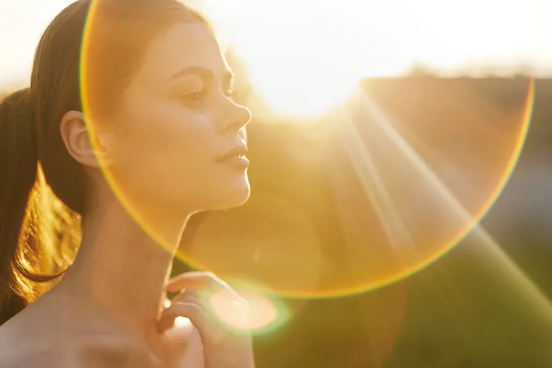 Young woman in profile with sunlight halo, showcasing serenity and beauty, perfect for health, wellness, or nature themed projects