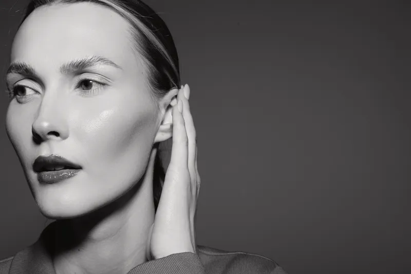 Closeup of a fair skinned Caucasian woman touching her ear looking away, studio portrait with soft lighting concept of beauty.