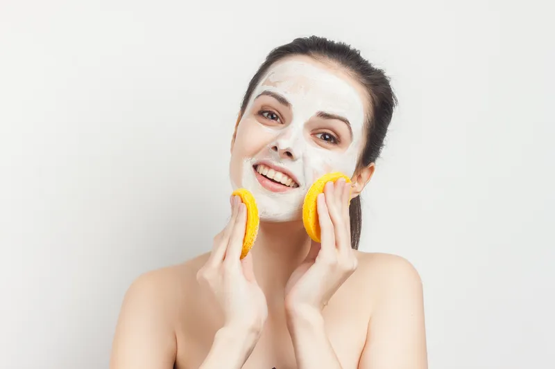 Женщина держит в руках ключи, крем-маску, скраб и губки