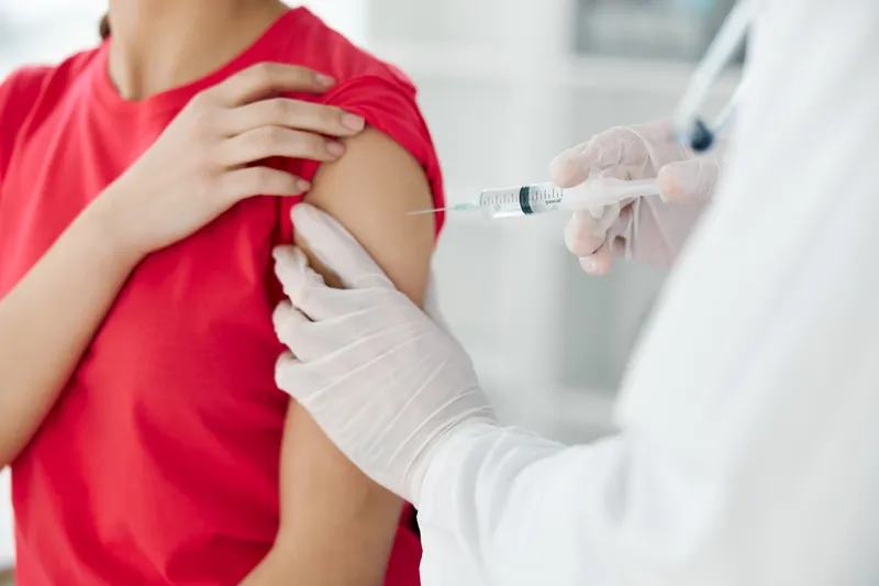 Врач крупным планом делает инъекцию вакцины в плечо женщины-пациента