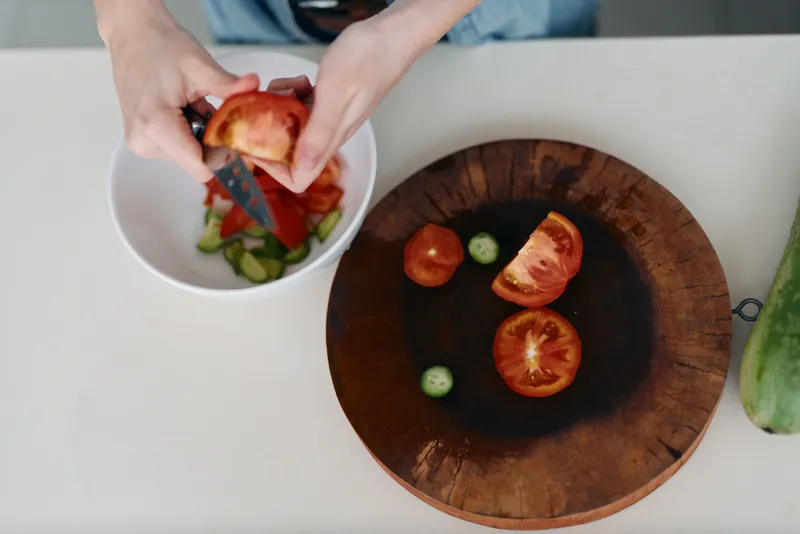 Свежий, полезный и вкусный салат из органических спелых овощей на деревянной тарелке выглядит ярко и аппетитно