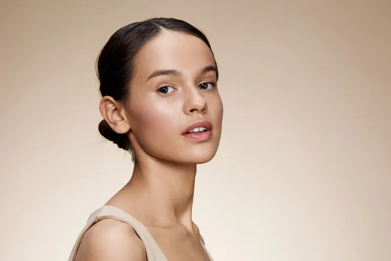 Elegant young model with smooth skin against a soft beige background, embodying beauty, confidence, and serenity, perfect for beauty and skincare themes