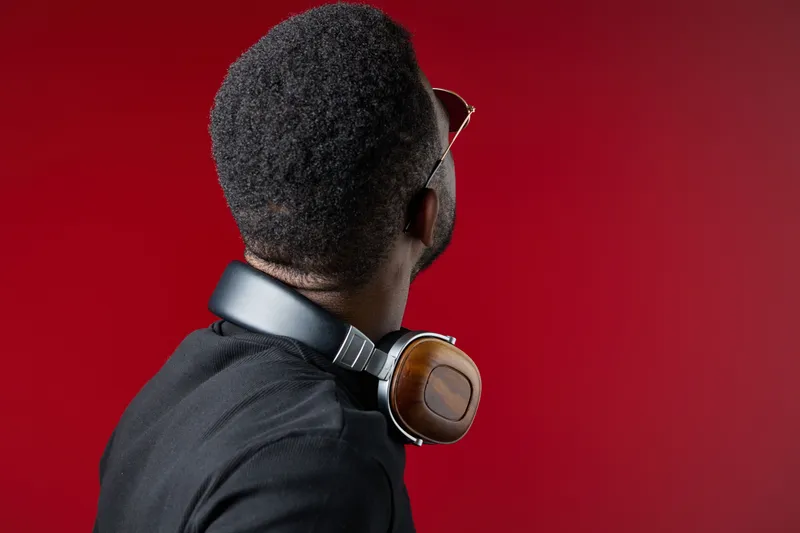 Stylish man with headphones looking back against a vibrant red background showcasing modern fashion and music culture, perfect for lifestyle promotions