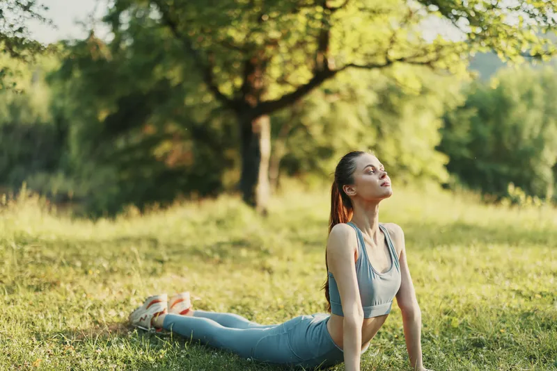 Young female practicing yoga outdoors in a serene green park, showcasing focus and calmness, ideal for wellness and fitness themes