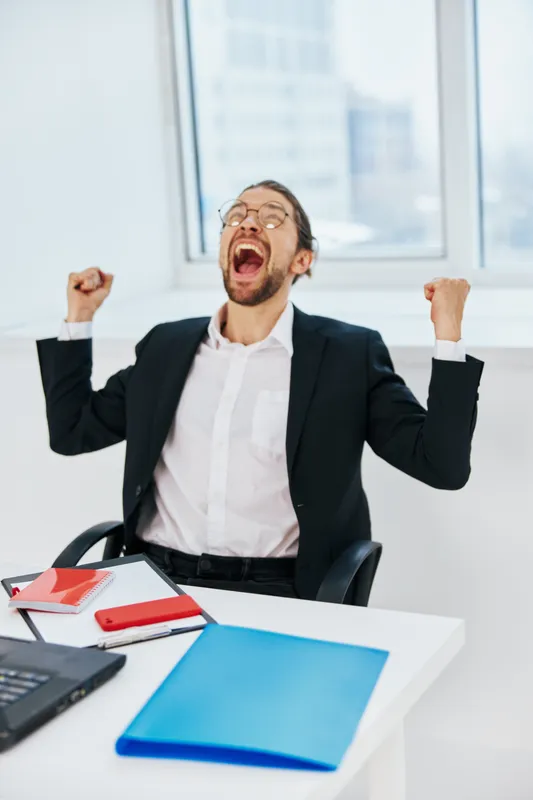 Мужчина в костюме с документами работает в офисе за ноутбуком