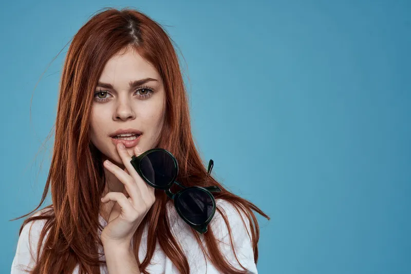 Симпатичная женщина с солнцезащитными очками в руках, образ жизни, эмоции, длинные волосы, косметика, осенний фон, белая футболка