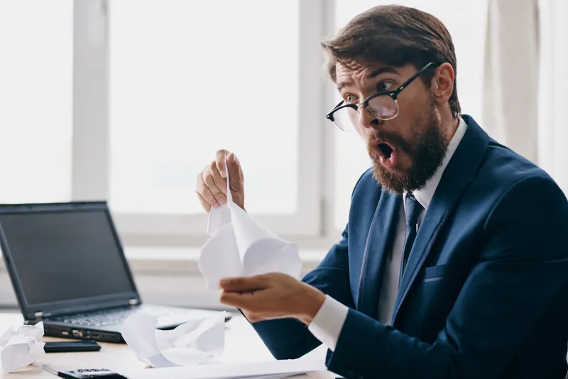 Менеджер работает за ноутбуком в офисе, испытывая недовольство