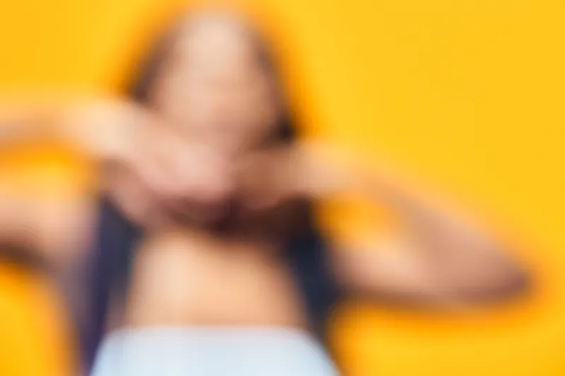 A blurred portrait of a woman with long hair against a vibrant yellow background, expressing confidence and tranquility in summer attire